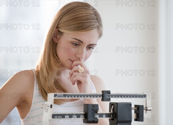 Young woman using measuring scales. Photographe : Daniel Grill