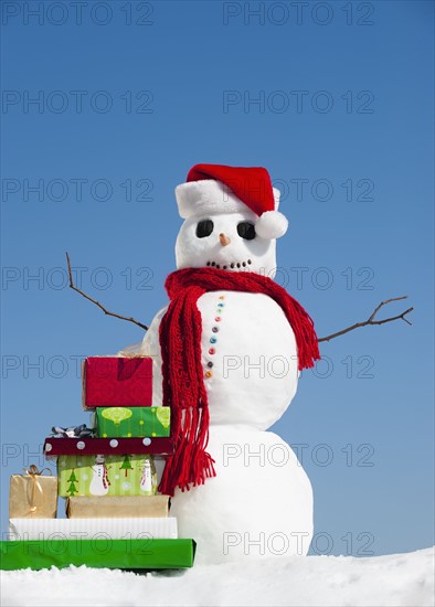 Snowman and Christmas presents, clear sky in background.