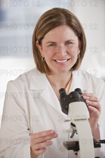 Portrait of female scientist using microscope.
