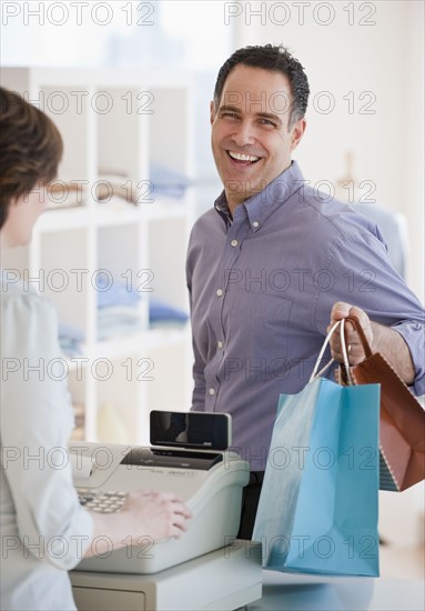 Man at checkout counter with bags.