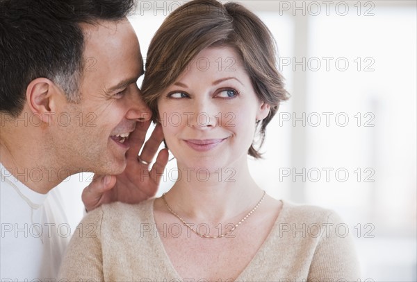 Man whispering to woman's ear.