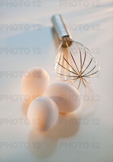 Studio shot of eggs and whisk.