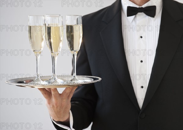 Champagne being served on a silver tray.