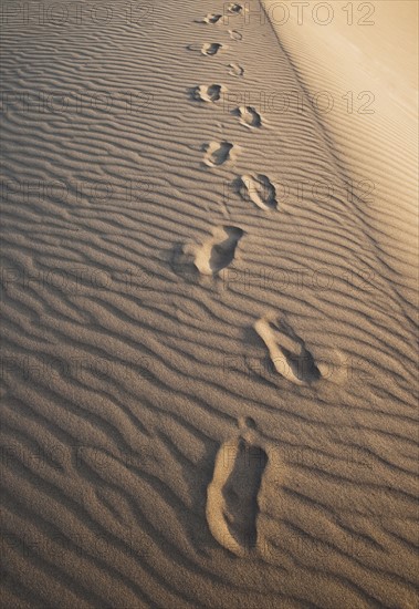 Sand dunes in the desert with footprints.