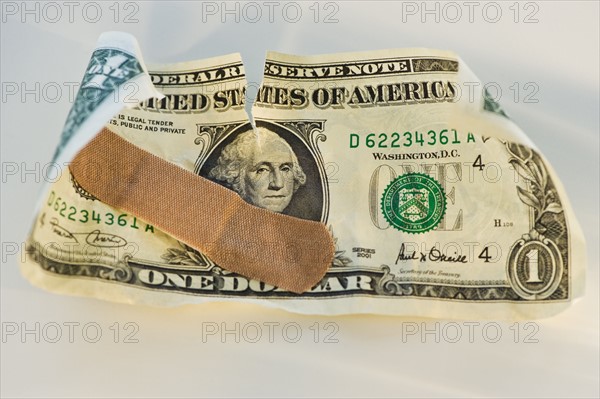 Crumpled dollar bill with a band aid