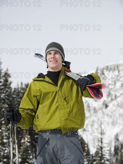 A downhill skier carrying skis