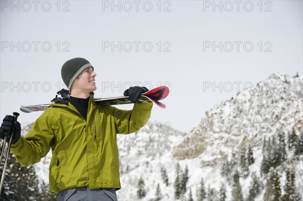 A downhill skier carrying skis