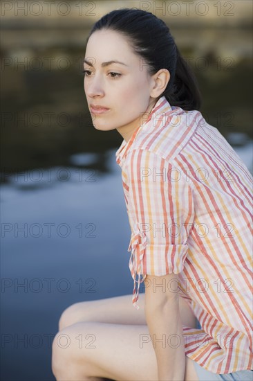 A woman sitting by water