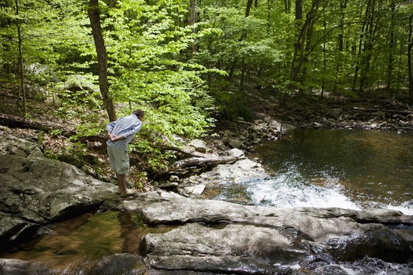 A man at a stream in the woods