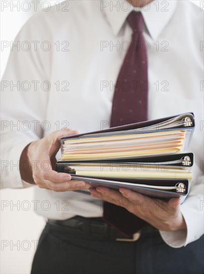 Businessman carrying binders.