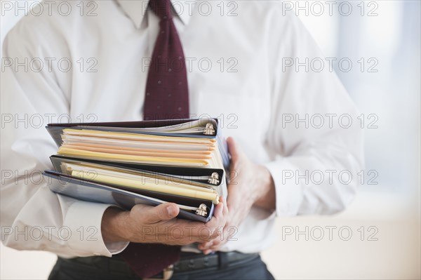 Businessman carrying binders.