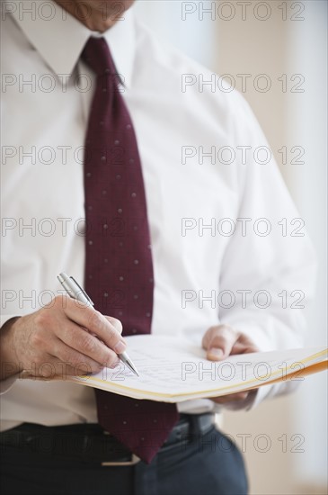 Businessman writing on folder.