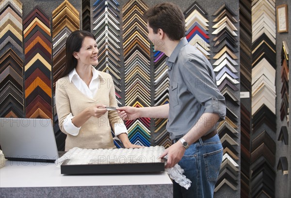 A woman helping a customer at a frame store.