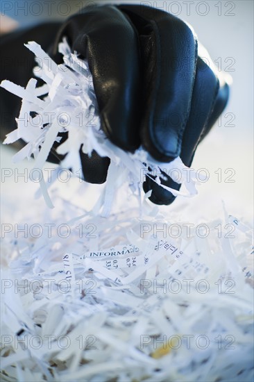 A gloved hand going through shredded papers.