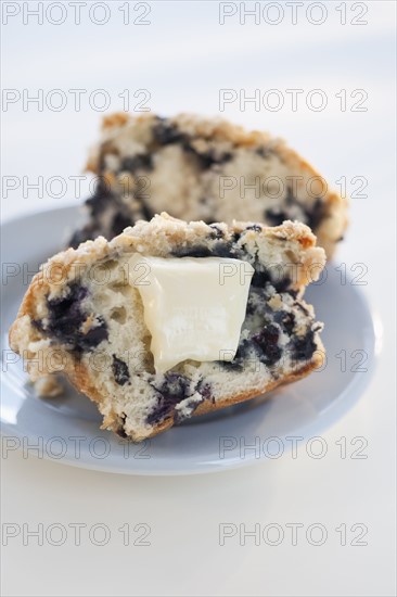 A blueberry muffin with butter.