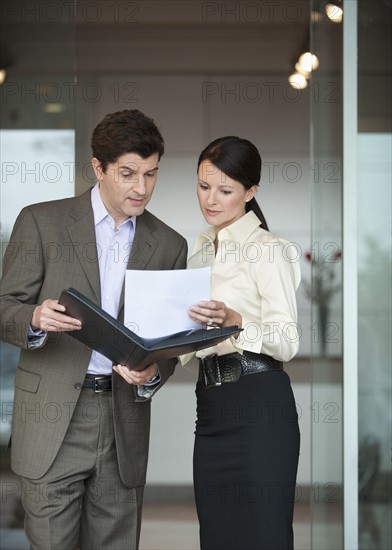 Two business people in office with paperwork.