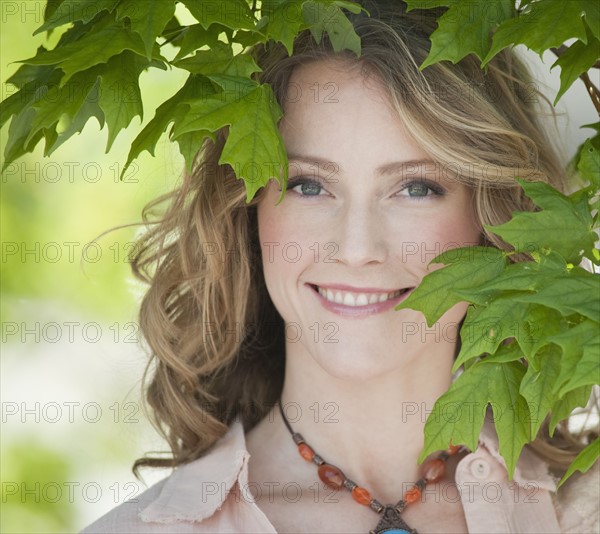 A woman outdoors surrounded in greenery.
