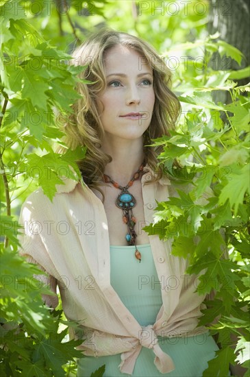 A woman outdoors surrounded in greenery.