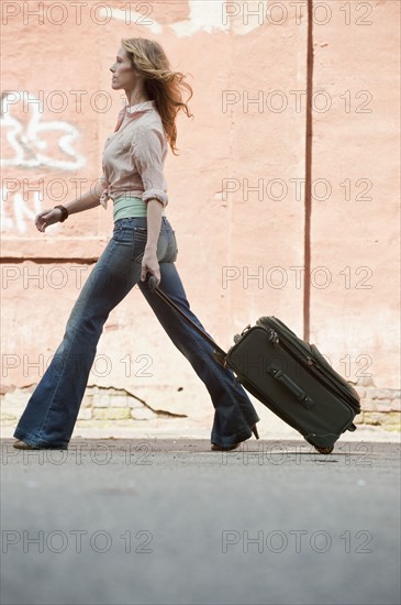 A woman walking with a suitcase.