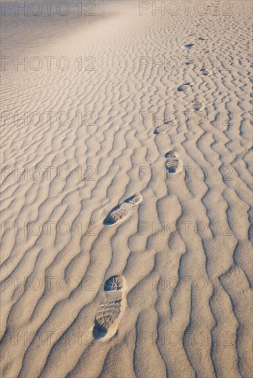 Sand dunes in the desert with footprints.