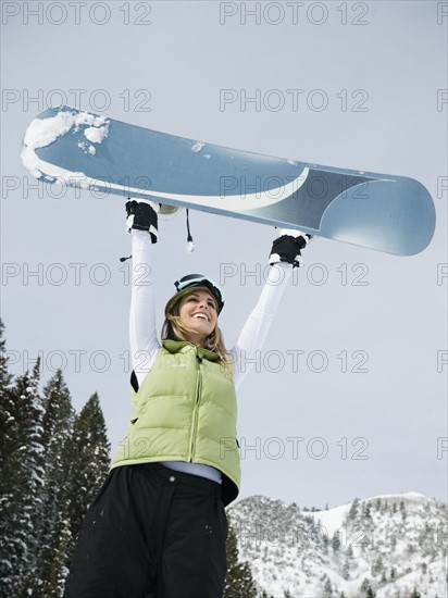 A snowboarder holding up her snowboard