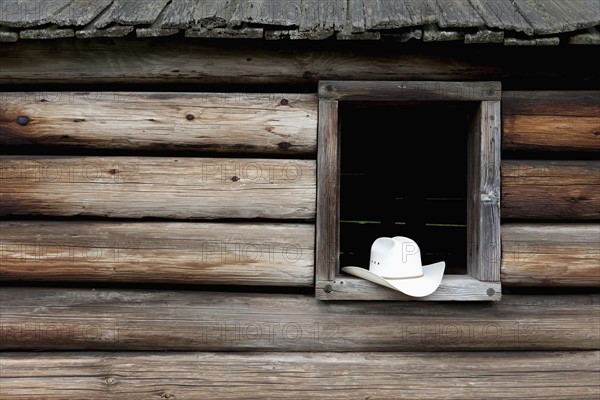 A cowboy hat in the window of a cabin