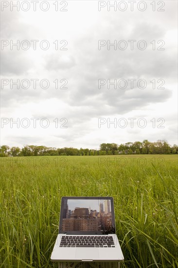 A computer in a field with an image of a city