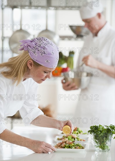 Chefs making salad in a kitchen.