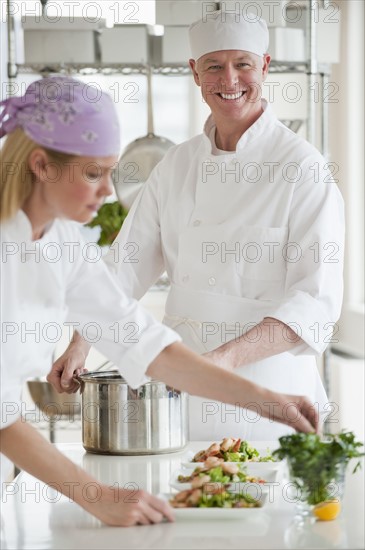 Chefs making salad in a kitchen.