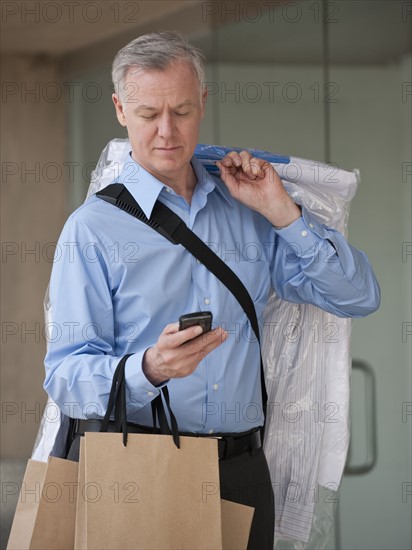 A man with dry cleaning and shopping bags.