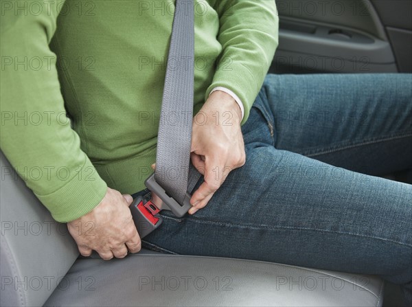 Man buckling seat belt in car.