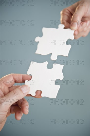 Hands holding puzzle pieces.