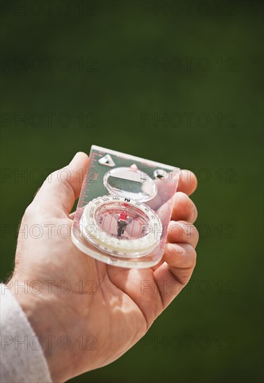 A hand holding a compass.