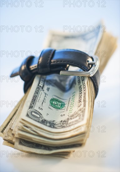 A watch around a stack of money.