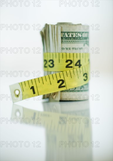 A measuring tape around bank notes.