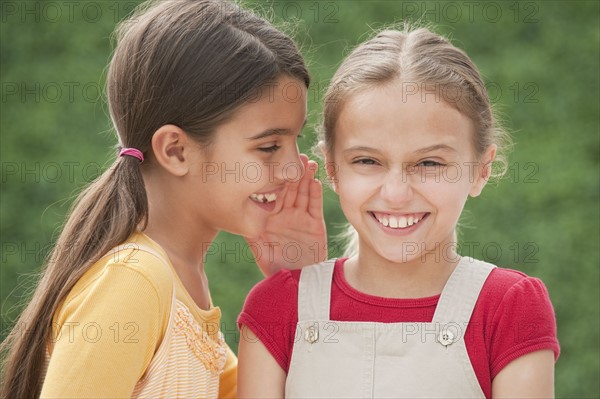 Two girl friends whispering.