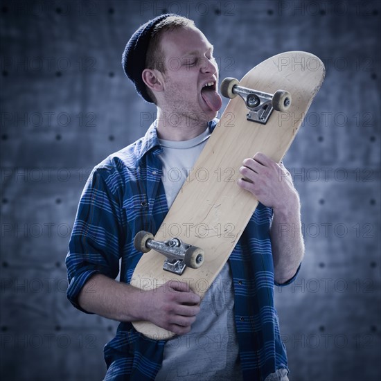 Male skateboarder licking board