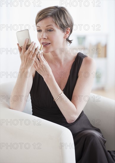 Woman putting on lipstick.