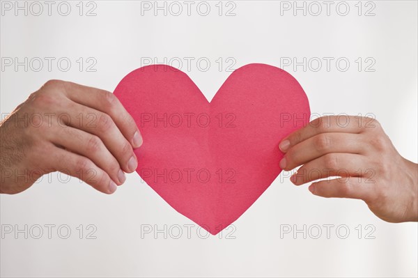 Two hands holding paper heart.