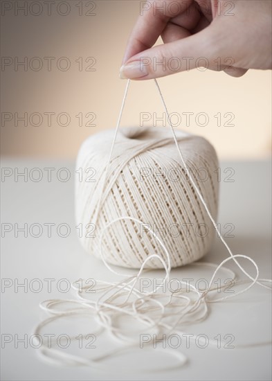 Hand pulling ball of string.