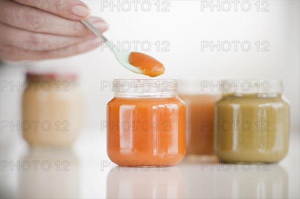 Hand spooning baby food.