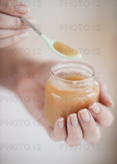 Hand spooning baby food.