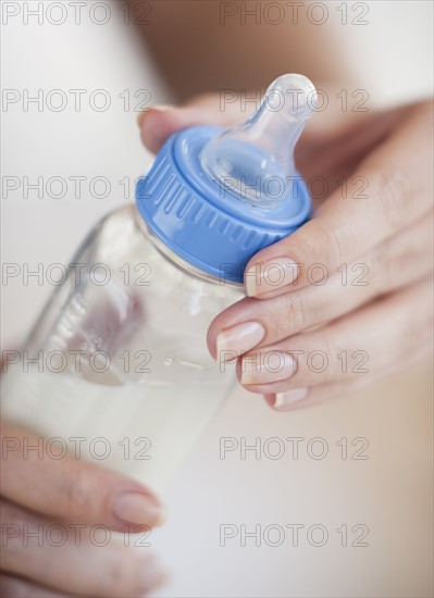 Hands holding baby bottle.