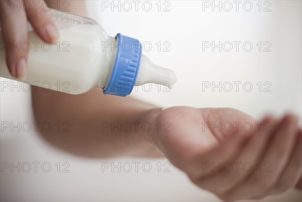 Hands holding baby bottle.