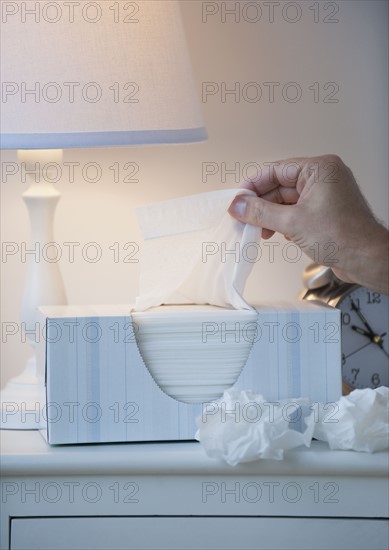 Hand pulling tissue out of box.