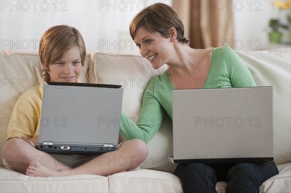 Mother and son on laptops.