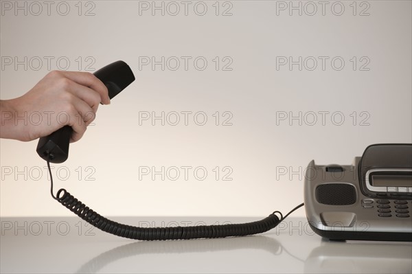 Hand on phone receiver.