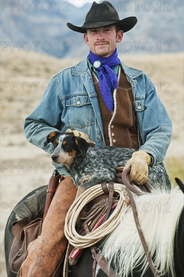 Cowboy and dog on horse.