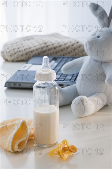 Baby bottle beside laptop.
