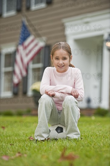 Girl sitting on soccer ball.